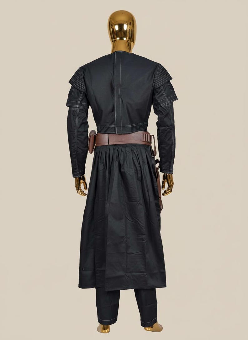 May include: Black costume with white stitching details, displayed on a mannequin. The outfit includes a long coat, pants, and a brown belt with pouches. The mannequin has a gold head.