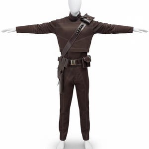 May include: A brown costume displayed on a mannequin. The outfit includes a long-sleeved top, pants, a belt with pouches, and a shoulder strap. The stitching is a lighter brown, creating a contrast. The mannequin's arms are outstretched.