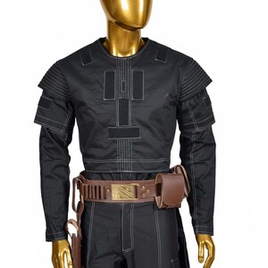May include: Black costume with white stitching, featuring a long-sleeved top with shoulder accents and a matching pair of pants. A brown leather belt with a gold buckle and a holster with a brown pouch complete the outfit.