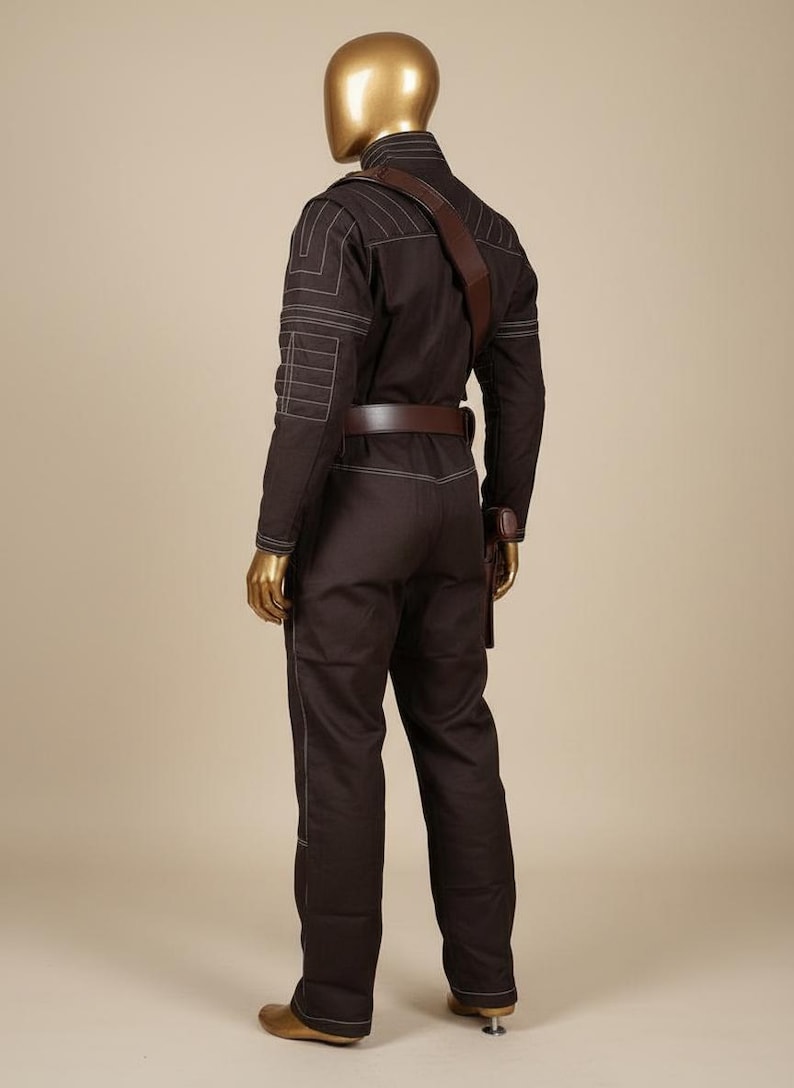 Puede incluir: Mono marr&oacute;n con detalles de costuras blancas, cintur&oacute;n marr&oacute;n y correa para el hombro marr&oacute;n. El mono tiene bolsillos en las mangas y las piernas. El maniqu&iacute; tiene cabeza y manos doradas.