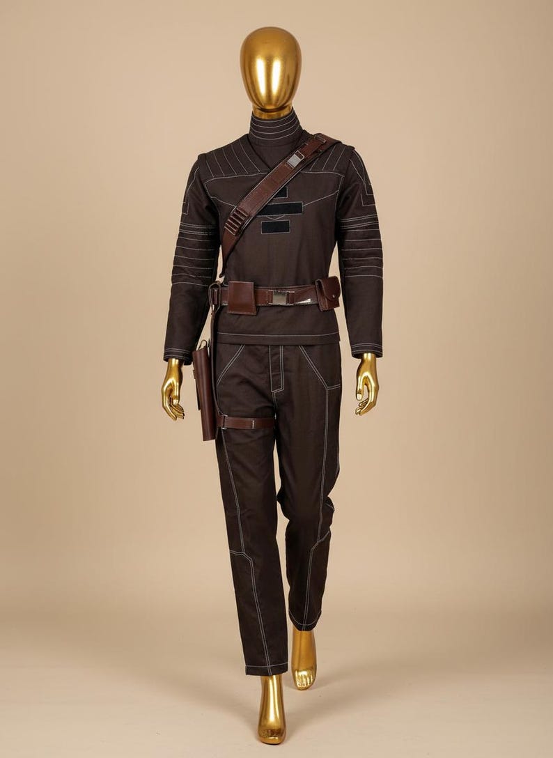 Puede incluir: Un disfraz marr&oacute;n con costuras blancas, que incluye una parte superior de manga larga y pantalones. El atuendo incluye un cintur&oacute;n marr&oacute;n, una correa para el hombro y una funda. El maniqu&iacute; tiene cabeza y manos doradas.
