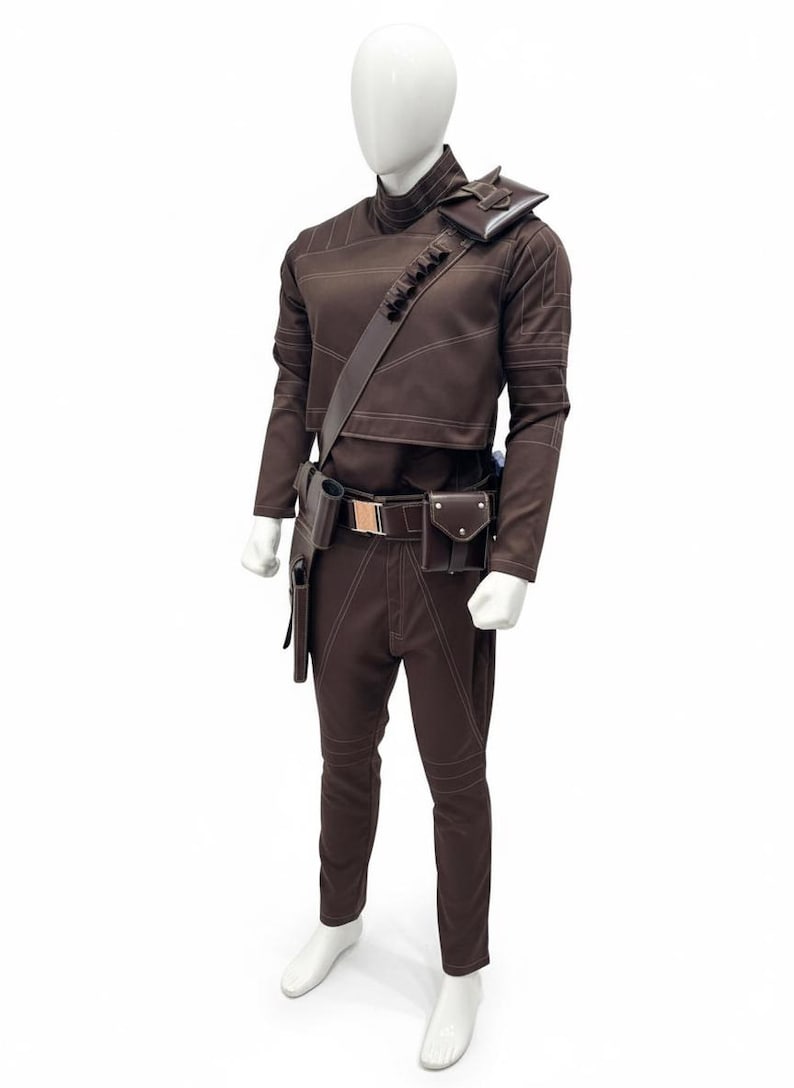 May include: A brown costume displayed on a mannequin. The outfit includes a long-sleeved top, pants, and a belt with pouches. White stitching accents the seams. A shoulder strap and holster are also included. The mannequin is on a white background.