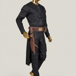 May include: Black costume with white stitching details, displayed on a gold mannequin. The outfit includes a long-sleeved top, pants, and a brown belt with a holster. The mannequin's head and hands are also gold.