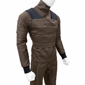 May include: Brown jumpsuit with a high collar and long sleeves, displayed on a mannequin. The suit features white stitching details and black accents on the shoulders and cuffs. The overall design suggests a utilitarian or workwear aesthetic.