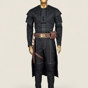 May include: Black costume with white stitching, displayed on a mannequin. The outfit includes a long-sleeved top, pants, and a long coat. A brown belt with a pouch and a holster are also included. The mannequin has a gold-colored head and hands.