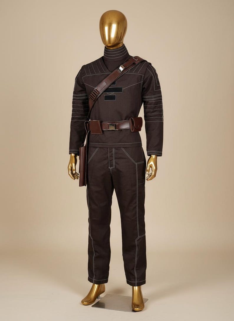 Puede incluir: Un uniforme marr&oacute;n con costuras blancas, exhibido en un maniqu&iacute;. El atuendo incluye una parte superior de manga larga, pantalones y un cintur&oacute;n con funda. Una correa de hombro marr&oacute;n y un cuello alto completan el look.