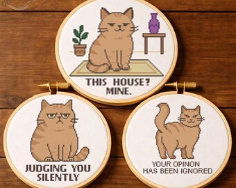 May include: Three round embroidery hoops with cross-stitch cat designs. One says "THIS HOUSE? MINE.", another says "JUDGING YOU SILENTLY", and the last says "YOUR OPINION HAS BEEN IGNORED". Each features a brown cat.