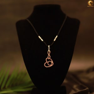 May include: A copper wire pendant shaped like a stylised heart with a twisted texture, suspended from a dark brown cord necklace. The cord features two small silver-toned metal accents on each side, connecting to the central copper heart pendant.