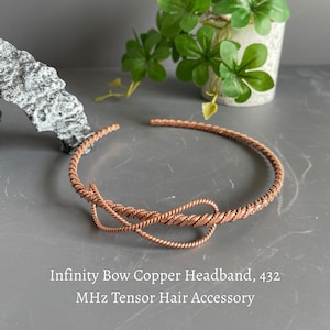 May include: A copper headband featuring a twisted wire design shaped into an infinity bow. The accessory is labeled as an Infinity Bow Copper Headband, 432 MHz Tensor Hair Accessory. The metal has a warm, metallic reddish-brown finish.
