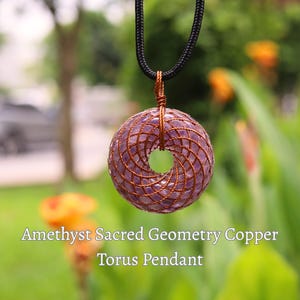 May include: Amethyst Torus pendant with copper wire wrapping, suspended from a black cord. The pendant features a donut shape with a spiral design. The text "Amethyst Sacred Geometry Copper Torus Pendant" is visible.