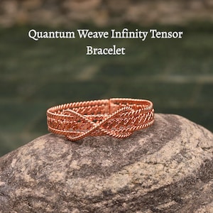 May include: A copper-colored bracelet with a woven design. The bracelet is labeled "Quantum Weave Infinity Tensor Bracelet". The bracelet is resting on a gray rock with a blurred green background.