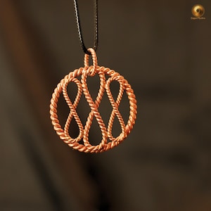 May include: A copper-colored pendant necklace with a circular design. The pendant features a woven rope-like pattern forming a circle with intertwined infinity symbols. The necklace hangs from a black cord against a blurred background.