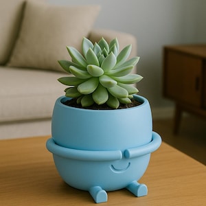 May include: A light blue, whimsical planter with a smiling face and small feet, holding a green succulent plant. The planter has a rounded shape with a band around the middle. The plant pot is on a wooden table.