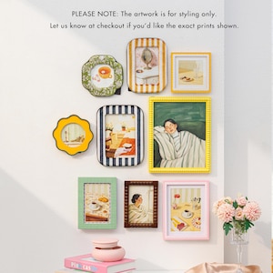 Puede incluir: Una colección de marcos de fotos decorativos en varias formas y colores, incluyendo verde, amarillo y rosa, se disponen en una pared blanca. Los marcos contienen obras de arte. El texto en la pared dice: "PLEASE NOTE: The artwork is for styling only. Let us know at checkout if you'd like the exact prints shown."