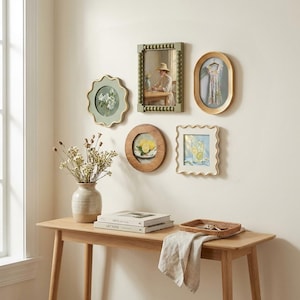May include: A gallery wall arrangement featuring five decorative frames in various shapes and colors, including a scalloped green frame, a beaded rectangular frame, an oval gold frame, a round wood frame, and a scalloped white frame.
