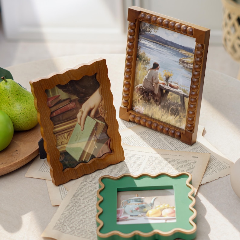 May include: Three decorative wooden picture frames. Two are brown with ornate detailing, one with a scalloped edge and the other with a beaded border. The third frame is green with a scalloped edge. Each frame holds a different image.