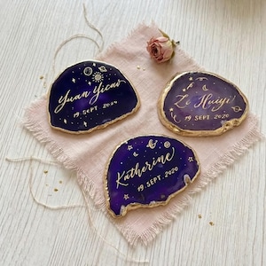 May include: Three custom-made, dark purple agate coasters with gold edges. Each coaster features handwritten gold calligraphy with names and dates: "Yuan Yicao 19 SEPT 2020", "Ze Huiyi 19 SEPT 2020", and "Katherine 19.SEPT. 2020".