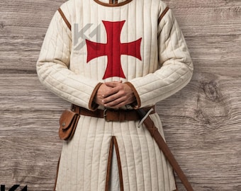 May include: Cream-colored quilted gambeson with a large red cross emblem on the chest. The medieval garment has brown trim, a high collar, and a split front. A brown leather belt, pouch, and sword complete the historical attire.