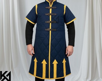 May include: A navy blue quilted gambeson with yellow trim and arrow accents. The short-sleeved garment features brown leather straps and a diamond pattern. The collar and edges are trimmed in yellow. The garment is worn over a black long-sleeved shirt.