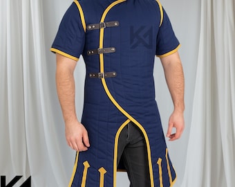 May include: A navy blue padded tunic with yellow trim and short sleeves. The tunic features a high collar, decorative brown leather straps, and a split front design. The Knights Armoury logo is visible in the lower left corner.