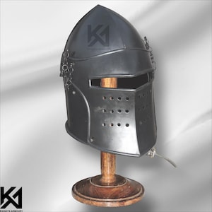 May include: A black medieval helmet with a pointed top, eye and mouth openings, and small ventilation holes. The helmet is displayed on a wooden stand. The text "KNIGHTS ARMOURY" is visible on the helmet.
