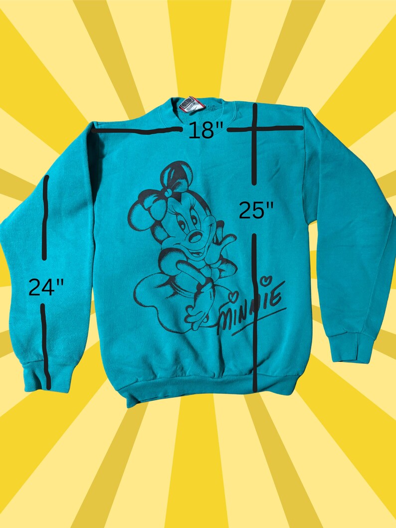 May include: Teal sweatshirt featuring a black graphic of Minnie Mouse with a bow. The sweatshirt measures 18 inches across the chest, 25 inches in length, and 24 inches for the sleeve length. The word "Minnie" is written in a cursive font.