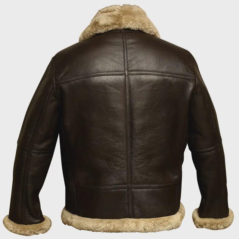 May include: A dark brown leather jacket featuring a shearling collar and cuffs. The jacket has a classic design with a front zipper and multiple panels. The shearling is a light tan colour, providing a contrast to the dark brown leather.