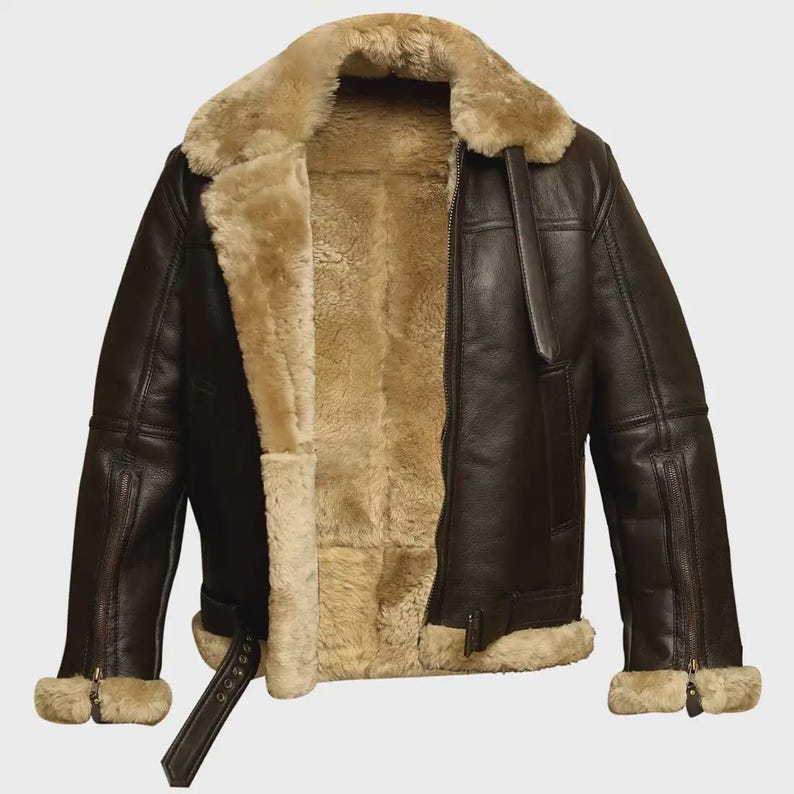 May include: A brown leather jacket with a shearling lining and collar. The jacket has a zip closure, side pockets, and a waist belt. The cuffs also have zips. This outerwear is designed for warmth and style.