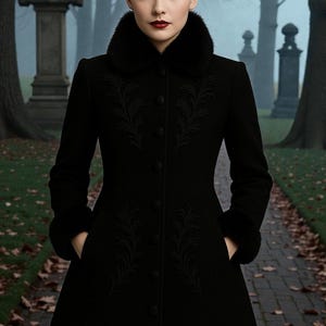 May include: A black coat with a faux fur collar and cuffs. The coat features intricate embroidered floral designs on the front and sleeves. The coat is buttoned up and has pockets. The background shows a path in a cemetery.