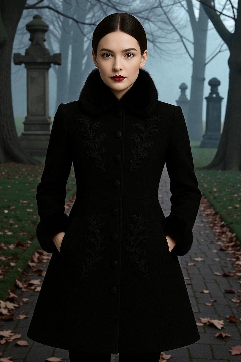 May include: A black coat with a faux fur collar and cuffs. The coat features intricate embroidered floral designs on the front and sleeves. The coat is buttoned up and has pockets. The background shows a path in a cemetery.