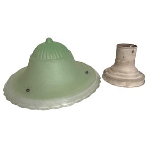 May include: A light green, dome-shaped glass lamp shade with a ribbed top and a scalloped edge, accompanied by a separate, circular, off-white metal light fixture base with a central socket and three small mounting holes around the perimeter.