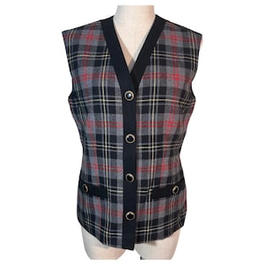 May include: A sleeveless plaid vest in gray, black, red, and yellow. The vest has a black trim, a V-neck, and four black buttons. Two pockets are outlined with black trim and gold-colored accents.