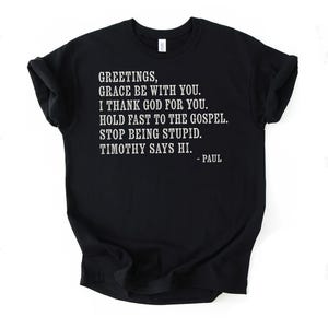 Black t-shirt with white text reading "Greetings, grace be with you. I thank God for you. Hold fast to the gospel. Stop being stupid. Timothy says hi. - Paul."