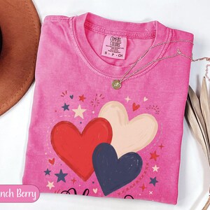 Pink t-shirt with red, white, and blue hearts and stars design.