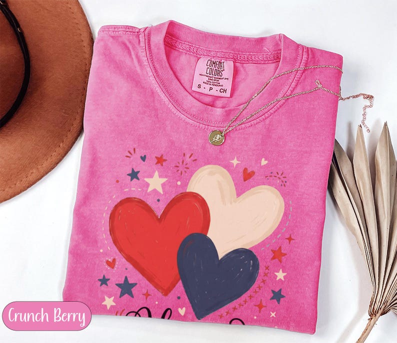 Pink t-shirt with red, white, and blue hearts and stars design.