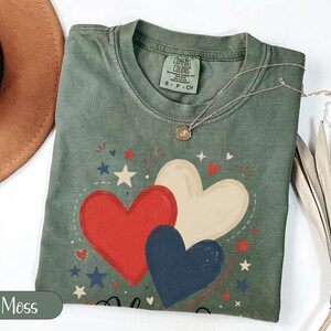 Green t-shirt with red, white, and blue hearts and stars graphic.