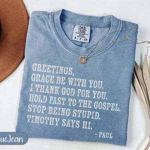 Blue t-shirt with "Greetings, Grace Be With You" text and a palm frond.
