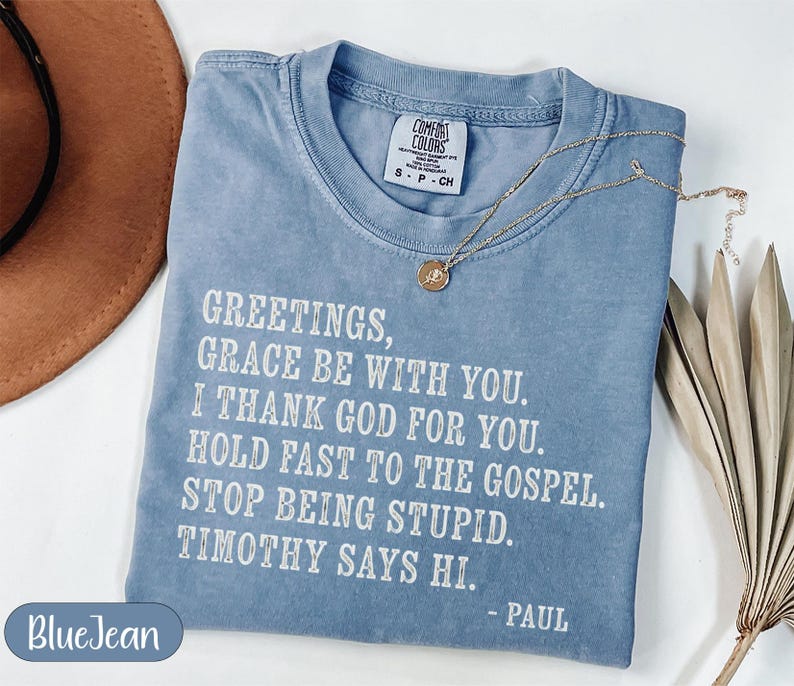 Blue t-shirt with "Greetings, Grace Be With You" text and a palm frond.