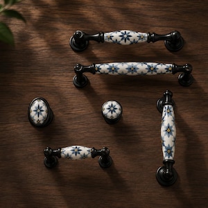 May include: A collection of cabinet hardware including three horizontal drawer pulls, one vertical drawer pull, and two round knobs. Each piece features a white ceramic center with a blue and yellow floral pattern and black metal ends.