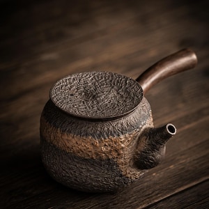 May include: A textured ceramic teapot with a dark wooden handle and lid. The teapot has a spout and a tan band around the middle. The background is a dark wooden surface.