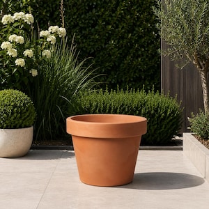 Op de afbeelding: Een grote, ronde plantenbak in terracotta-kleur met een brede, platte rand. De pot heeft een gladde, matte afwerking en een taps toelopend lichaam dat smaller wordt naar de basis toe. Het is een eenvoudige, functionele pot voor planten.