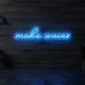 May include: A blue neon sign displaying the words "make waves" in a cursive font. The sign is mounted on a dark wood-paneled wall. The room has a dark blue floor and a potted plant in the corner.