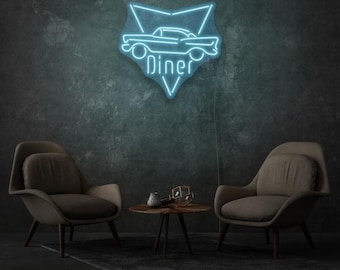 May include: A blue neon Diner sign in the shape of a car, fixed to a dark grey wall. The sign is above two armchairs and a small table with decorative items. The scene is dimly lit, creating a retro atmosphere.