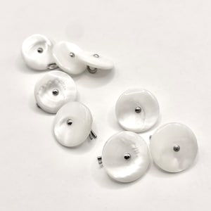May include: A set of eight white mother of pearl buttons with silver metal shanks.