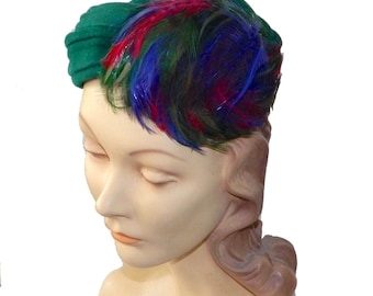 May include: A green velvet hat with a colorful feather accent. The hat is worn on a mannequin head.