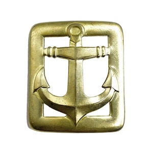 May include: A rectangular brass belt buckle featuring a centred anchor motif. The design consists of a solid outer frame with an open space surrounding the embossed anchor, which is positioned vertically within the centre of the metal buckle.