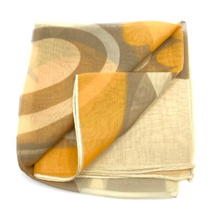 May include: A folded sheer scarf with a retro design. The scarf features a pattern of curved and geometric shapes in shades of beige, brown, and yellow. The scarf is made of a lightweight, flowing fabric.