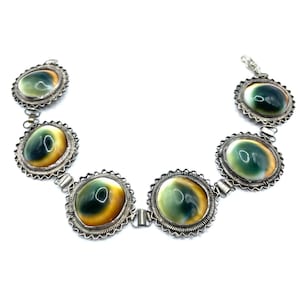 May include: A silver chain necklace with five round green, yellow, and white abalone shell pendants.