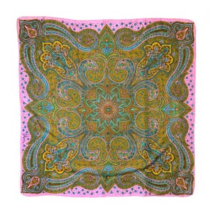 May include: A square silk scarf featuring a vibrant paisley pattern in shades of olive green, teal, and yellow, framed by a bright pink border with small blue floral accents. The signature Vera is printed in the lower left corner of the fabric.