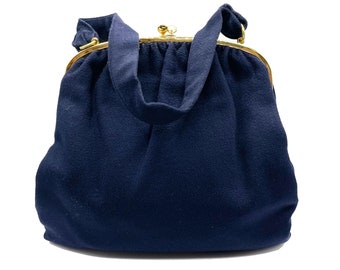 May include: A dark blue fabric handbag with a gold clasp and a single strap.